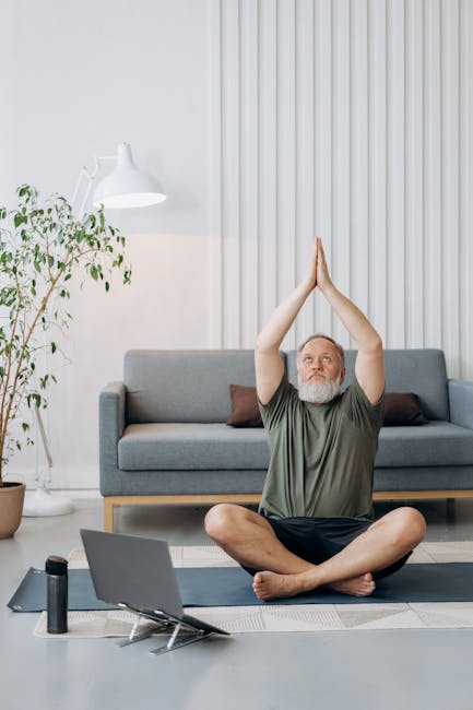 Man sitting cross-legged on a floor cushion meditating in a brightly lit room